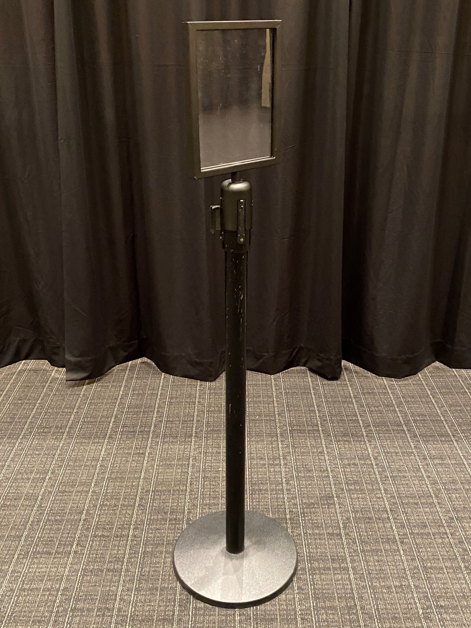 A black stanchion with a clear plastic sign on top.